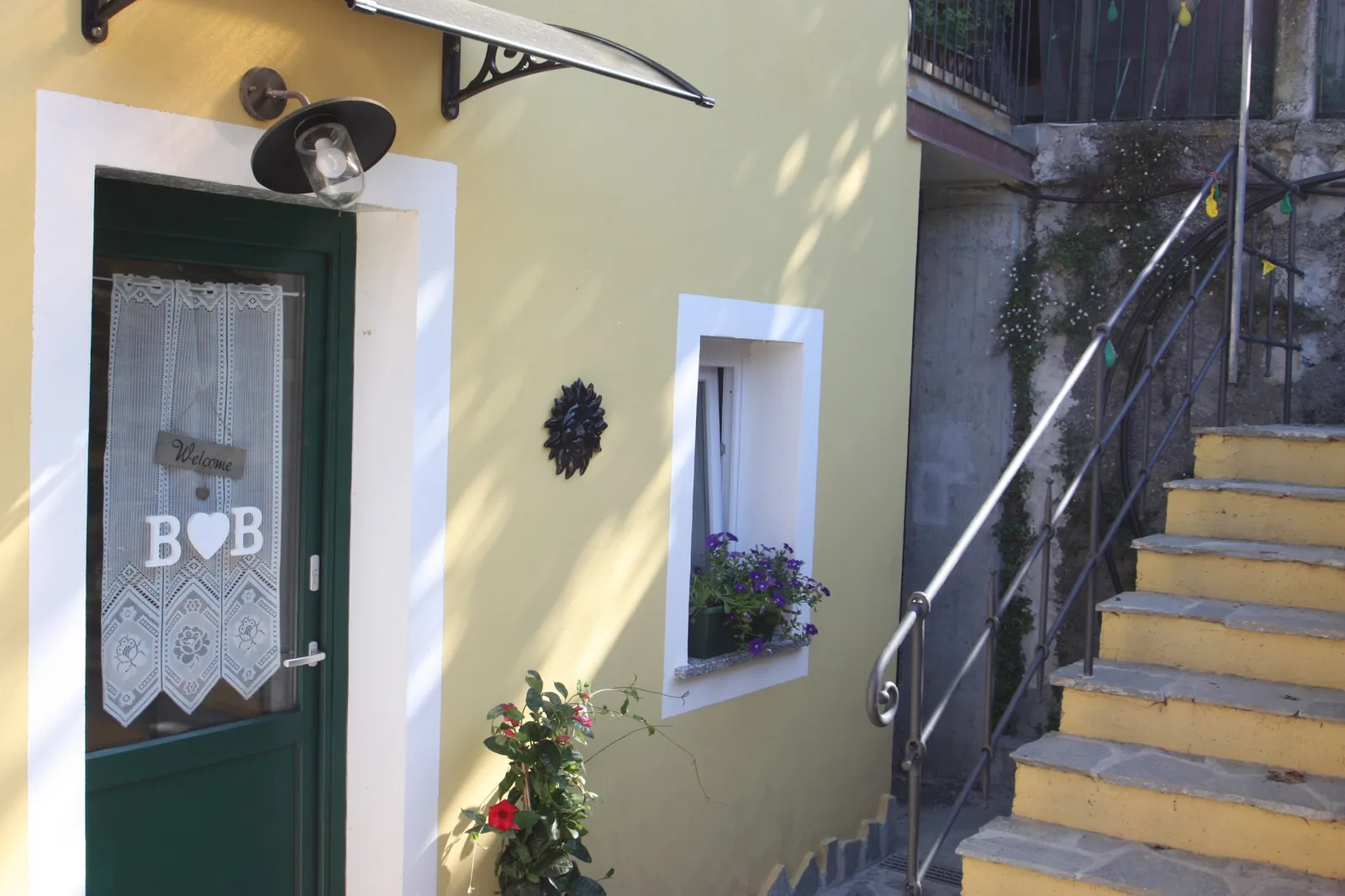 La casa gialla di Cà di Toni con la porta verde e la scalinata in pietra