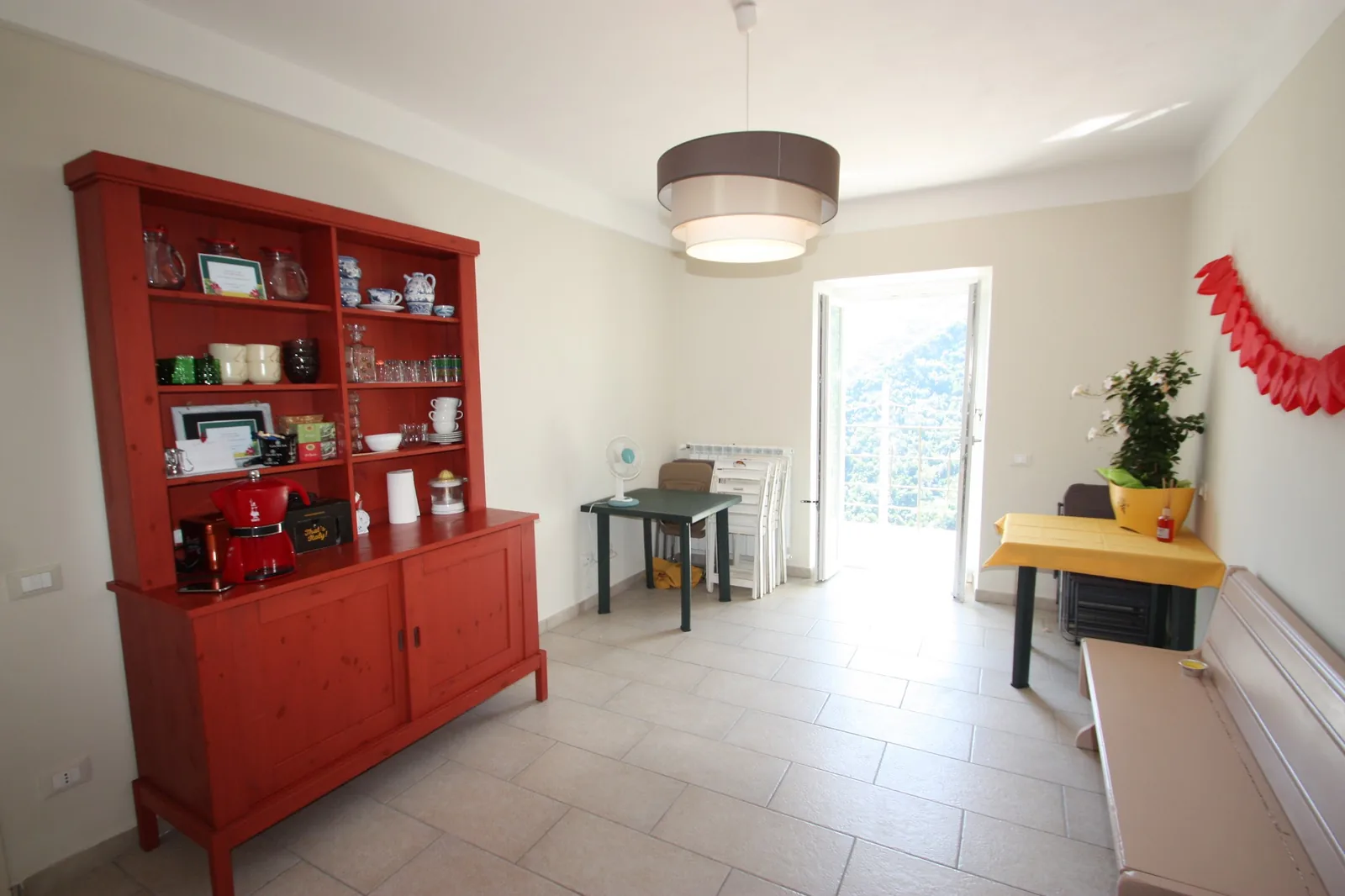 La sala della colazione con la credenza rossa e la portafinestra sulla valle